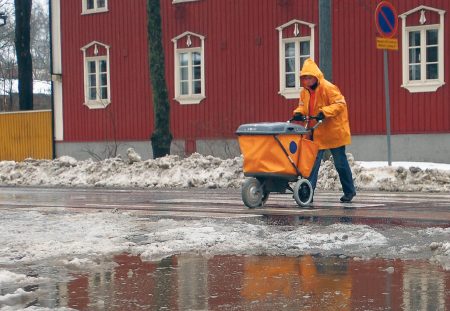 Postinjakaja työntää orasseja postikärryjä.