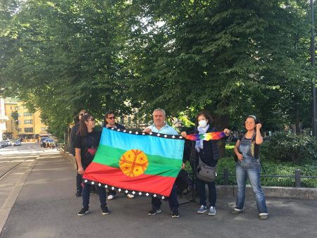 Ihmiset pitävät mapuchelippua yhdessä käsissään.