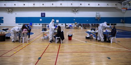 Terveydenhuollon työntekijät testaavat ihmisiä koronaviruksen varalta koripallokentälle perustetussa keskuksessa Ramat Ganissa