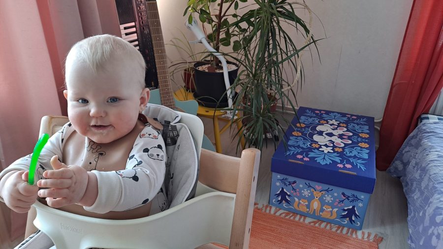 Aini Packalén syö puuroa Pispalassa helmikuussa 2026. Taustalla Kelan vuoden 2024 äitiyspakkaus. Kuva Petra Packalén